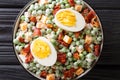 Easy English salad of raw green peas with boiled eggs, bacon and cheddar cheese with sauce close-up in a bowl on the table. Royalty Free Stock Photo