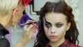 Easy Halloween Makeup. Girl in a beauty salon. Applying a stylistic pattern on the face of the model. The work of a master stylist