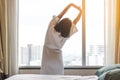 Easy lifestyle Asian woman waking up in weekend morning taking some rest relaxing in comfort city hotel room Royalty Free Stock Photo