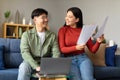 Smiling Korean Spouses Using Laptop Holding Bills Papers At Home Royalty Free Stock Photo