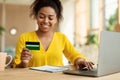 Easy payment and cashback concept. Smiling black lady doing online shopping at home using laptop and credit card Royalty Free Stock Photo