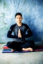 Easy Pose or Sukhasana is performed by a young man doing on the colorful mat wearing black attire. Royalty Free Stock Photo