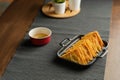 Easy recipe, snacks, minced pork meat filled fried wontons sort in black dish on grey placemat, brown wood table served with sweet Royalty Free Stock Photo