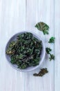 Easy three ingredient baked green kale chips with sea salt and olive oil, in gray bowl, vertical, top view