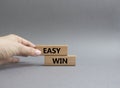 Easy win symbol. Wooden blocks with words Easy win. Beautiful grey background. Businessman hand. Business and Easy win concept.
