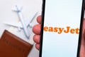 EasyJet Airline app on a smartphone screen with a plane and passport on the background. The concept of travel app