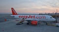 EasyJet passenger aircraft waiting for passengers to get onboard near sunset via an airbridge visible in the image