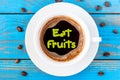 EAT FRUITS - inscription on top viewed morning coffee mug at blue wooden table Royalty Free Stock Photo