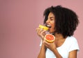 Eat grapefruit for the good of your health. Studio shot of an attractive young woman eating grapefruit against a pink Royalty Free Stock Photo