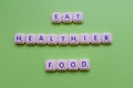 Motivational slogan: Eat healthier food, over a green background made with playing letters Royalty Free Stock Photo