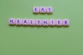 Motivational slogan: Eat healthier, over a green background made with playing letters Royalty Free Stock Photo