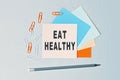 Eat Healthy - text on sticky note paper on gray background. Closeup of a personal agenda. Top view Royalty Free Stock Photo