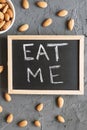 `Eat me` phrase written on a small blackboard and raw almond