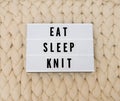 EAT SLEEP KNIT word on lightbox on knit background. Cozy compozition. Knit WOOL background. Royalty Free Stock Photo