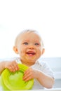 Eat smeared smiling baby girl playing with plate