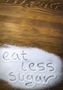 EAT LESS SUGAR written on pile of sugar