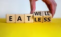 Eat well or eat less symbol. Businessman turns cubes and changes words `eat less` to `eat well`. Beautiful white and yellow