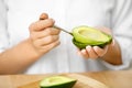 Eating Avocado. Woman Hands Peeling Fresh Avocado With Spoon