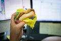 Eating breakfast at work in front of computer screen Royalty Free Stock Photo