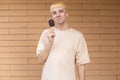 Eating Caucasian man dressed in a beige T-shirt, holding a bite of chocolate ice cream on a stick outside Royalty Free Stock Photo