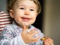 Eating cheerful baby girl with messy face