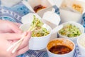 Eating Chinese take away food with chop sticks at home with bed sheets in the background. Spicy asian food in white box - salad,