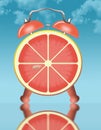 Eating citrus fruit for breakfast is illustrated with a slice of grapefruit pictured as the face of an alarm clock Royalty Free Stock Photo