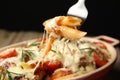 Eating delicious pasta casserole with fork against blurred black background, closeup Royalty Free Stock Photo
