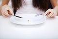 Eating disorder. Girl is holding a plate and trying to put a pea Royalty Free Stock Photo