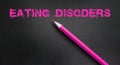 Eating disorder words written with pink pencil on dark background. Weightloss anorexia bulimia healthcare concept