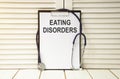 An eating disorder is written on a white sheet, which stands on a wooden table and a stethoscope.