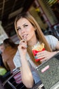 Eating french fries in fast food coffee shop or restaurant beautiful blond young woman with green eyes having fun, portrait Royalty Free Stock Photo