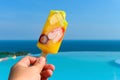 eating fresh fruit popsicle in front of a swimming pool with the ocean at the far end Royalty Free Stock Photo