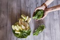 Eating healthy breakfast bowl with fresh fruits and vegetables as apple, pear and spinach. Woman hand holding a bunch of spinach. Royalty Free Stock Photo