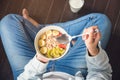 Woman holding bowl of cereal and granola and variety fruits and glass of milk on the floor. Royalty Free Stock Photo