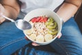 Eating healthy breakfast concept. Woman holding bowl of cereal and granola and variety fruits and glass of milk on the floor. Royalty Free Stock Photo