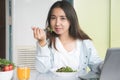 Woman holding dish of salad with variety vegetables and glass of orange juice on the floor.