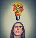 Eating healthy idea diet tips. Woman looking up light bulb made of fruits above head Royalty Free Stock Photo