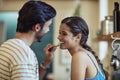 Eating healthy together. an affectionate young couple snacking while preparing a meal in their kitchen.