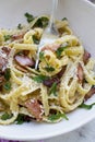 Eating pasta carbonara with a fork from a white bowl - white marble background Royalty Free Stock Photo