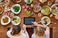 Women with tablet pc at table full of food