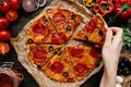 Eating pizza, top view. Hand taking slice of hot delisious pizza. Pizza ingredients on the wooden table Royalty Free Stock Photo