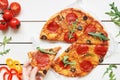 Eating pizza, top view. Hand taking slice of hot delisious pizza on the white wooden table Royalty Free Stock Photo