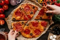 Eating pizza, top view. Hands taking slices of hot delisious pizza. Pizza ingredients on the wooden table Royalty Free Stock Photo