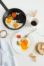 Eating in the process, fried eggs in a frying pan and on a plate, toast with avocado and a cup of coffee for breakfast. Royalty Free Stock Photo