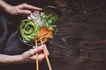 Eating raw vegan bowl with rice noodles, vegetables and avocado on wooden background. Top view with copy space Royalty Free Stock Photo