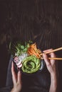 Eating raw vegan bowl with rice noodles, vegetables and avocado on wooden background. Top view with copy space Royalty Free Stock Photo