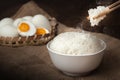 Eating rice with salted eggs by using chopsticks on wooden background