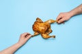 Eating roasted chicken on blue background. People hands grabbing chicken. Sharing food
