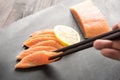 Eating salmon sushi with lemon on wooden background.